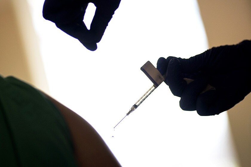 A syringe with the COVID-19 vaccine is about to go into an arm