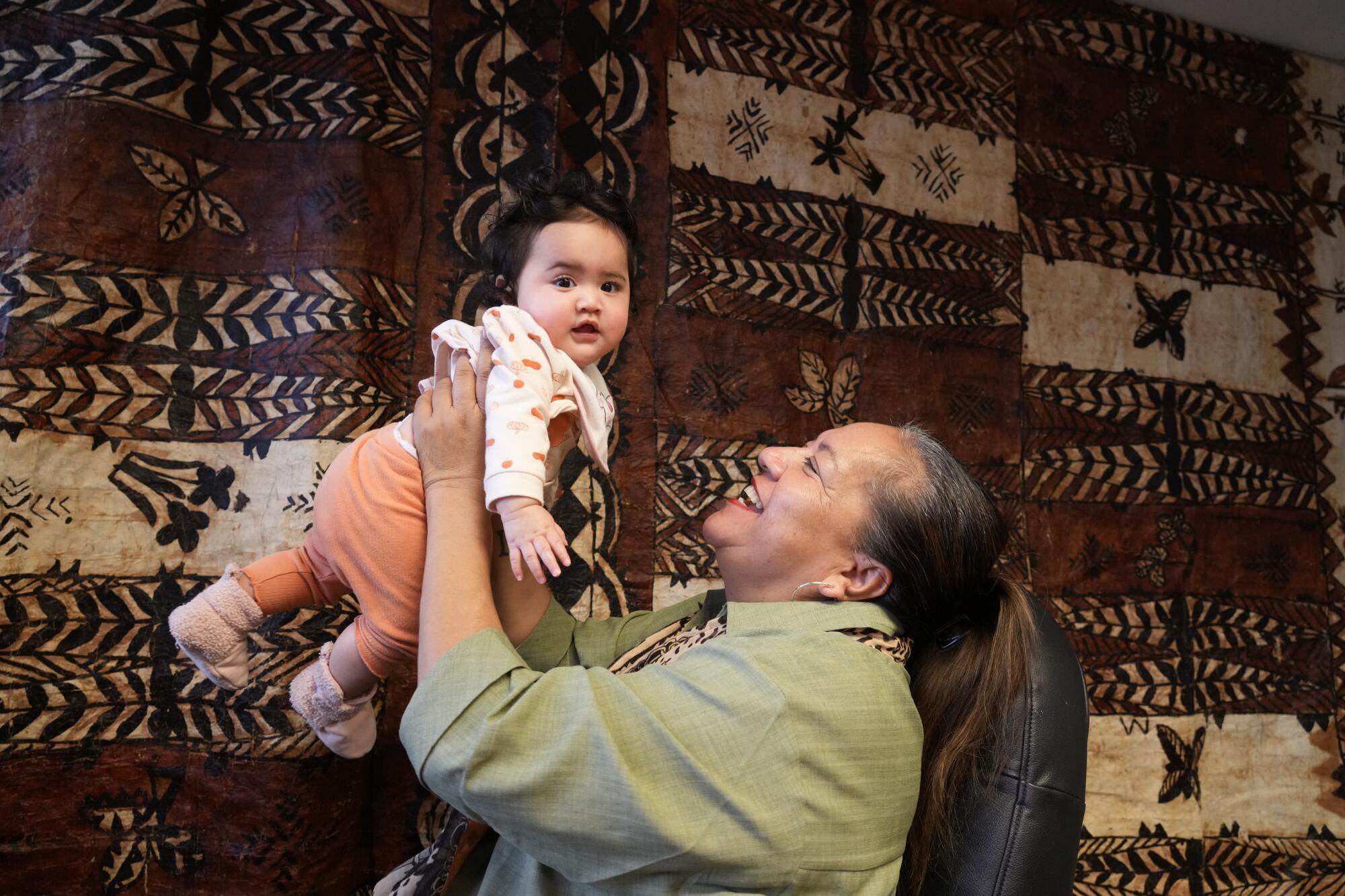 At the National Tongan American Society, Maryan Savini, a civil engagement worker, holds her granddaughter JoAnne Savini.