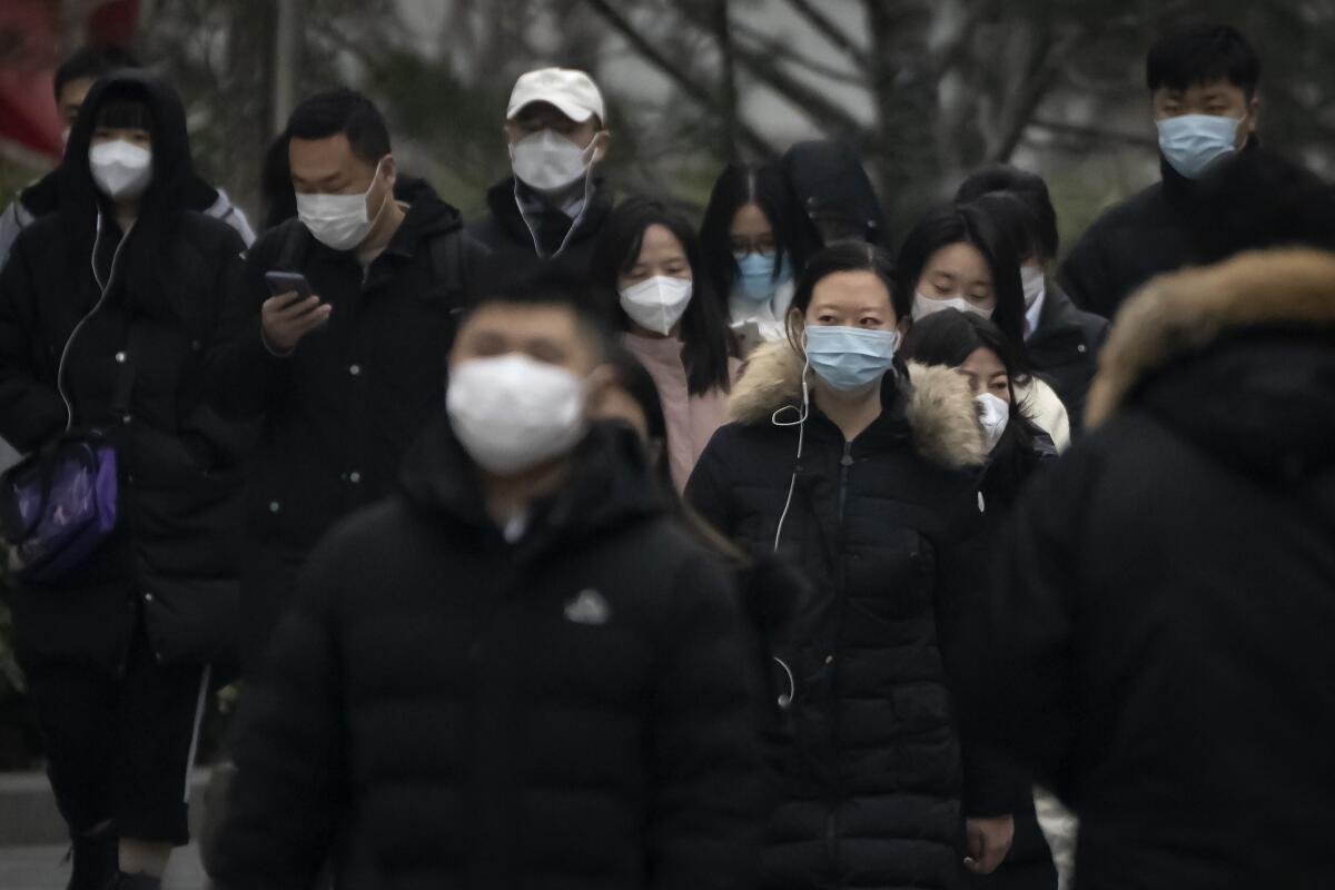 Transeúntes con mascarilla caminan por una calle de un distrito empresaria en el centro de Beijing
