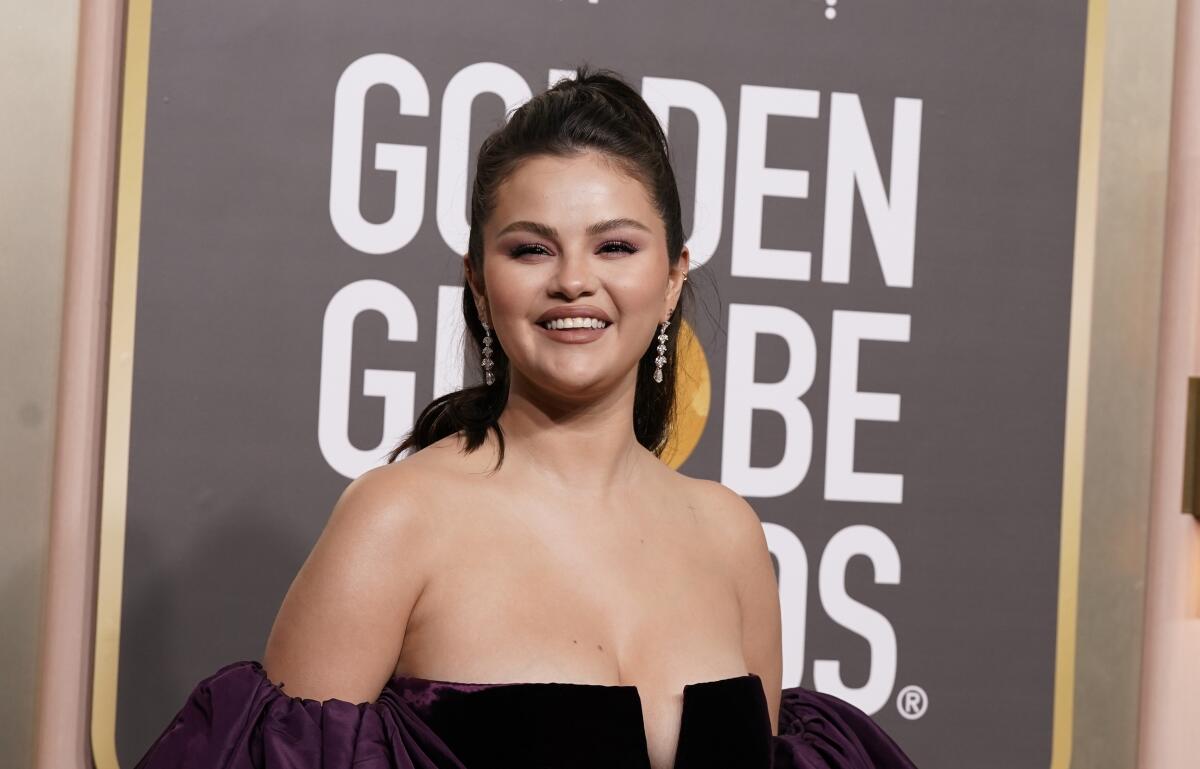 Selena Gomez smiles upon arrival at an awards show wearing a strapless black formal gown
