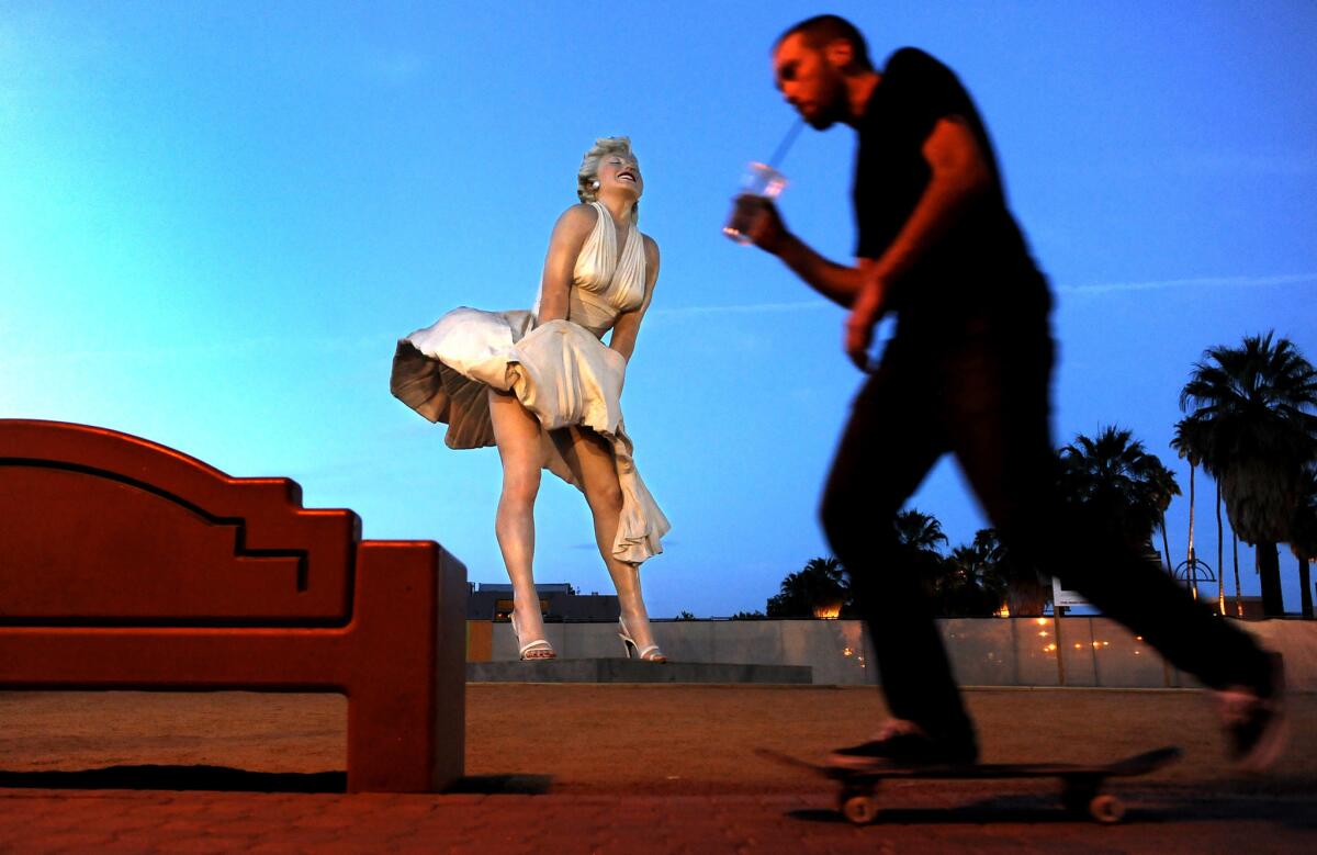 A skateboarder rides past a 26-foot statue of Marilyn Monroe in Palm Springs. The statue will be moved to New Jersey but residents hope to keep the art piece in the desert town.