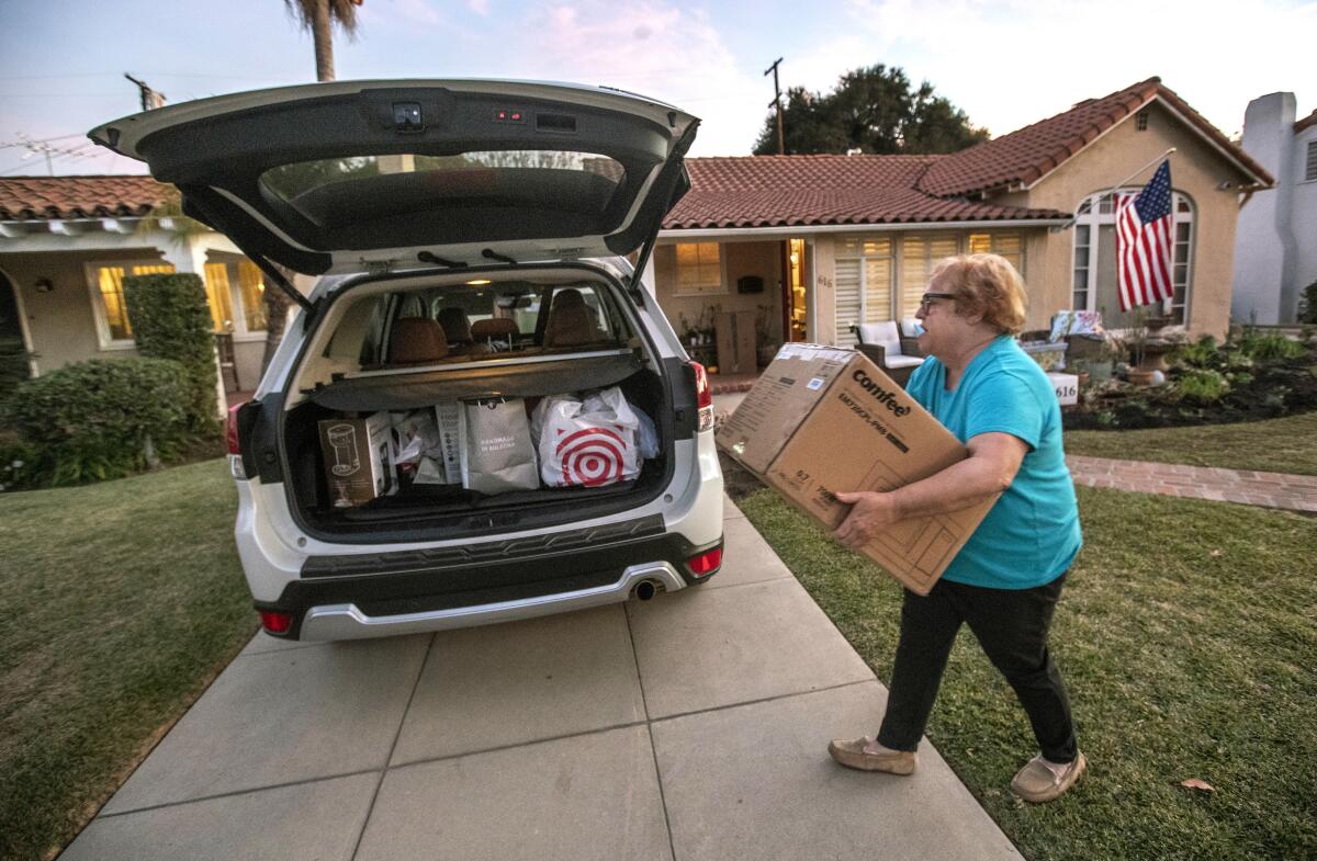 Jo Anne Kindler loads a box containing a microwave oven into the back of her car, a day before driving to her new home