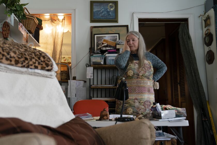 FILE - Nancy Rose, who contracted COVID-19 in 2021 and continues to exhibit long-haul symptoms including brain fog and memory difficulties, pauses while organizing her desk space, Tuesday, Jan. 25, 2022, in Port Jefferson, N.Y. Rose, 67, said many of her symptoms waned after she got vaccinated, though she still has bouts of fatigue and memory loss. A report from the Centers for Disease Control and Prevention released on Wednesday, May 25, 2022, found that up to a year after an initial coronavirus infection, 1 in 4 adults aged 65 and older had at least one potential long COVID health problem, compared with 1 in 5 younger adults. (AP Photo/John Minchillo)