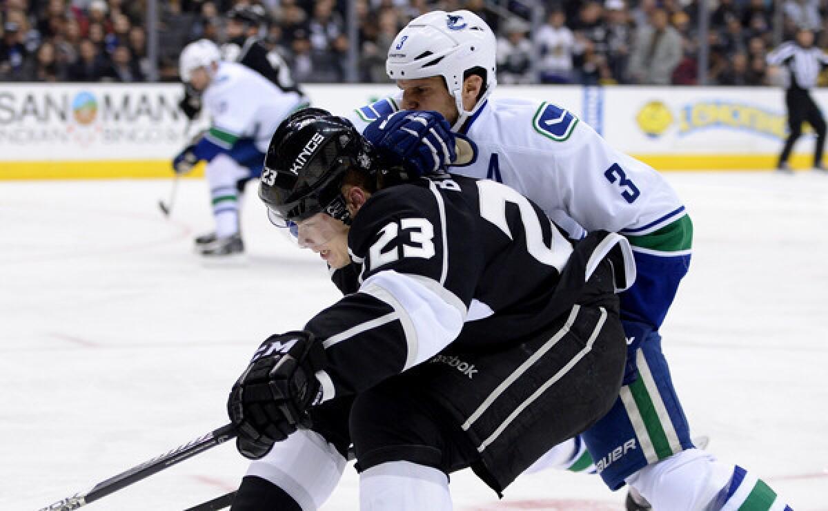 Kings captain Dustin Brown, front, battles Vancouver Canucks defenseman Kevin Bieksa for control of the puck during the second period of the Kings' 1-0 win Monday.