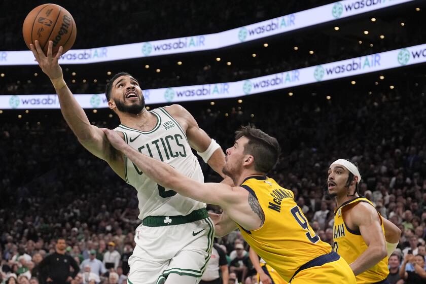 El alero de los Celtics de Boston Jayson Tatum lanza el balón superando al base de los Pacers de Indiana T.J. McCollum en el tiempo extra del juego 1 de las finales de la Conferencia Este el martes 21 de mayo del 2024. (AP Foto/Charles Krupa)