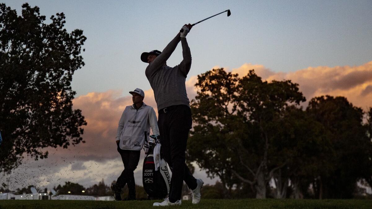 Adam Scott hits his approach shot into the second green as dusk falls on the course during the third round of the Genesis Open at Riviera Country Club.