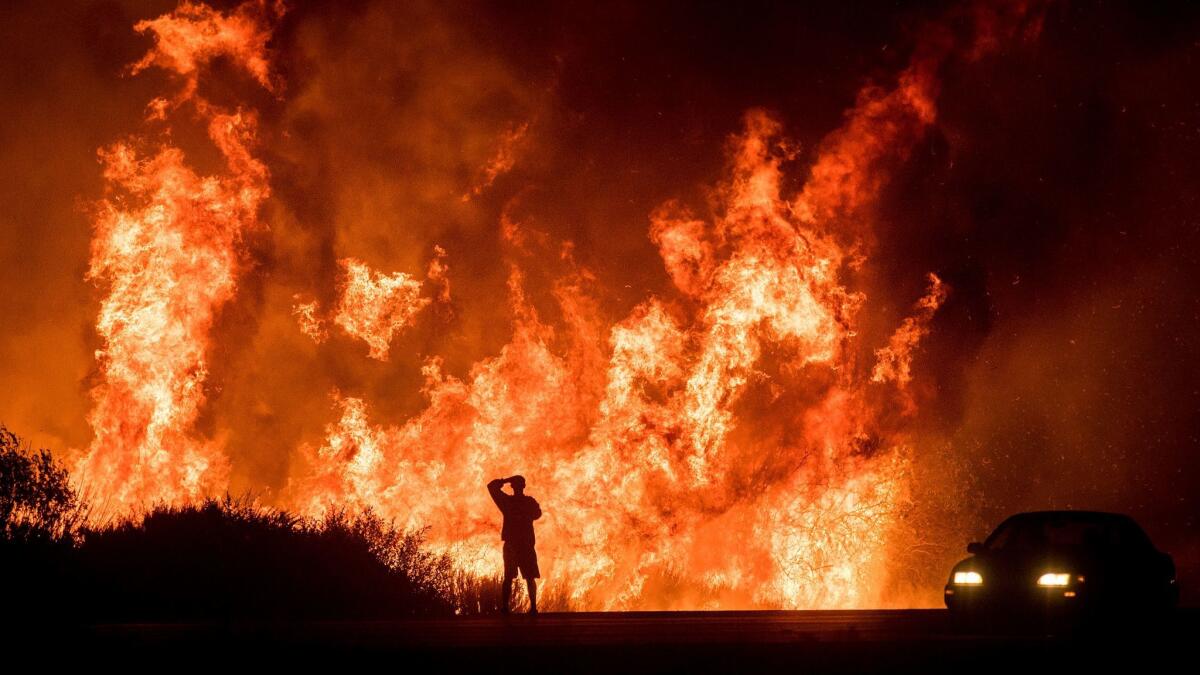 A motorist on Highway 101 watches flames from the Thomas fire leap above the roadway north of Ventura, Calif. on Dec. 6, 2017.