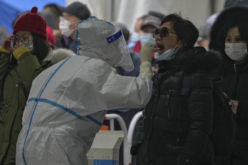 A woman get a throat swab at a mass coronavirus testing site in Beijing, Monday, Jan. 24, 2022. Chinese authorities have lifted a monthlong lockdown of Xi'an and its 13 million residents as infections subside ahead of the Winter Olympics. Meanwhile, the 2 million residents of one Beijing district are being tested following a series of cases in the capital. (AP Photo/Andy Wong)