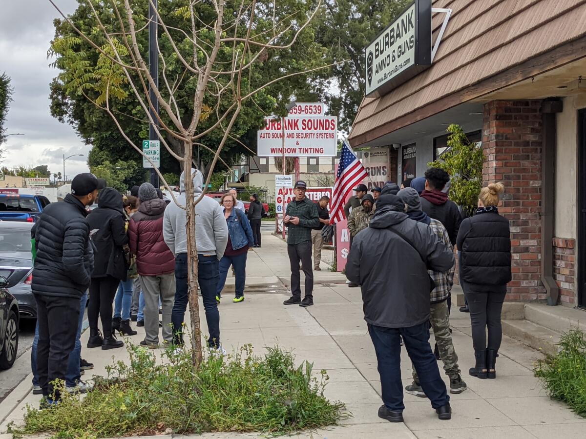 An employee of Burbank Ammo & Guns in Burbank talks to customers who were looking to purchase a firearm and ammunition in light of the coronavirus pandemic on Monday, March 16, 2020.