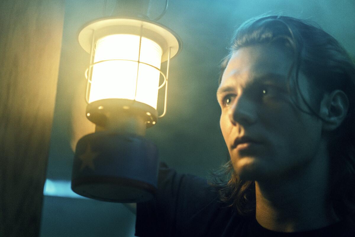 A man holds a lantern in a dark room
