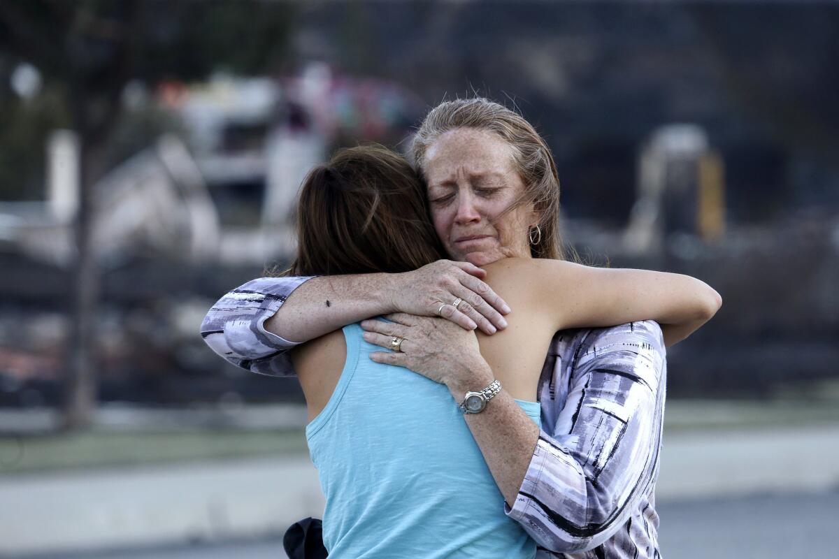 Julie Smith, right, hugs neighbor Renee Monson near the remains of Smith's home in Wenatchee, Wash.