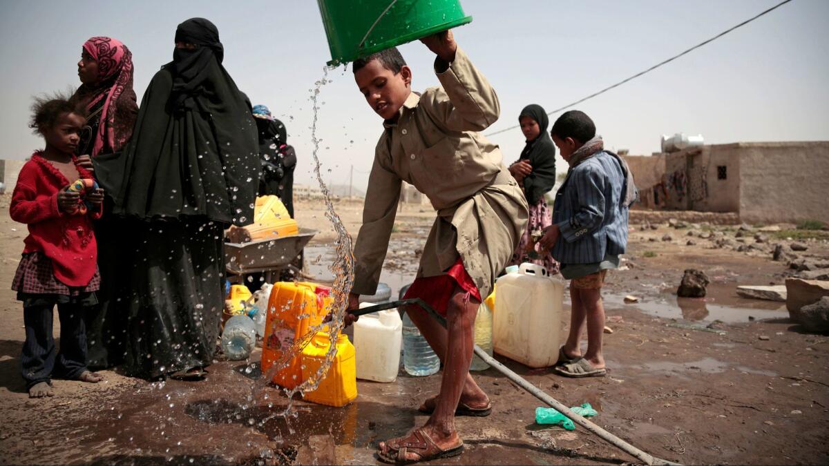 A boy rinses a bucket as he and others collect water from a well believed to be contaminated with cholera bacteria on the outskirts of Sana in Yemen on July 12, 2017.