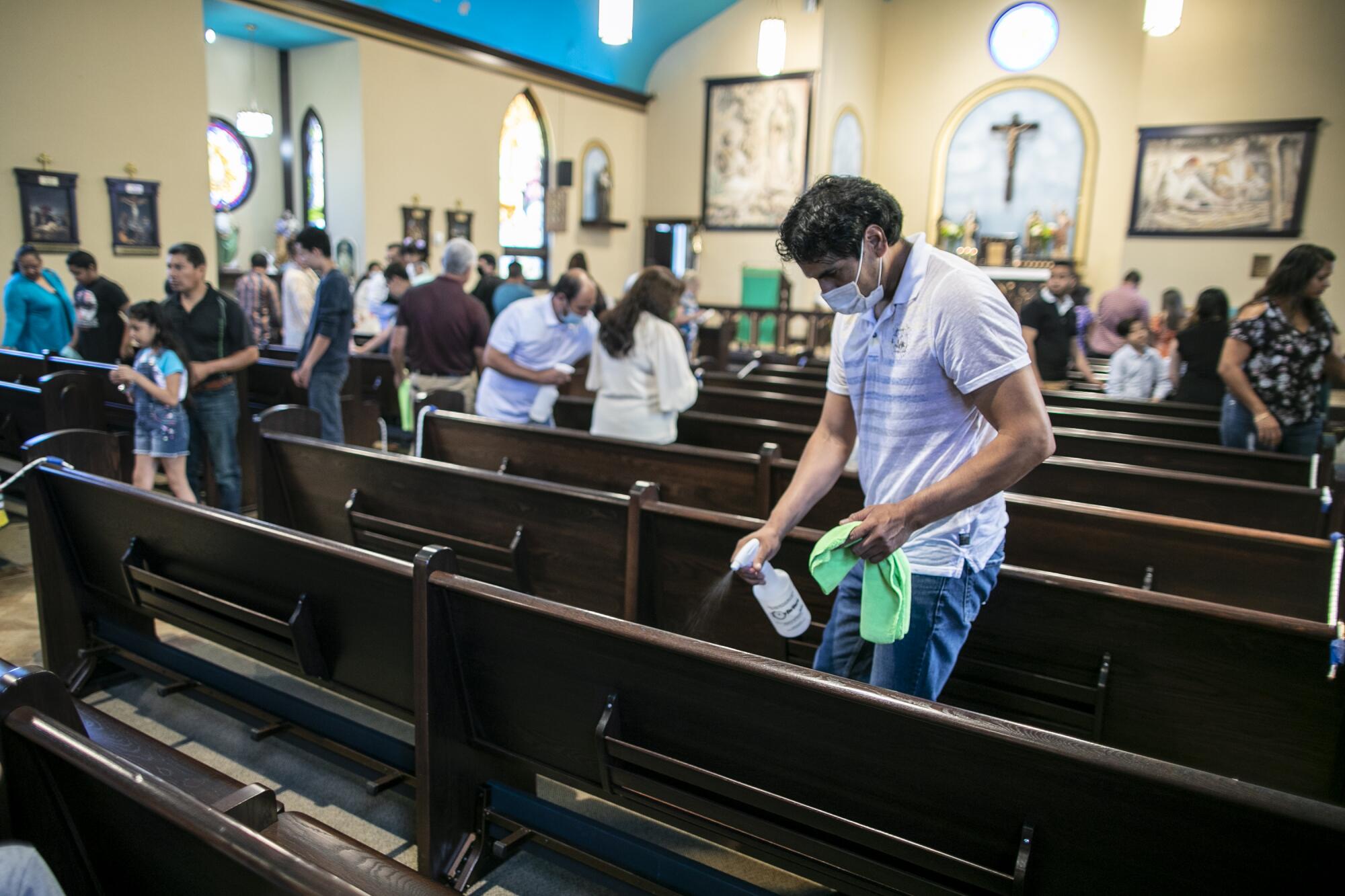 Saul Estrada, a butcher, sanitizes a pew following Sunday Mass at Our Lady of Guadalupe.
