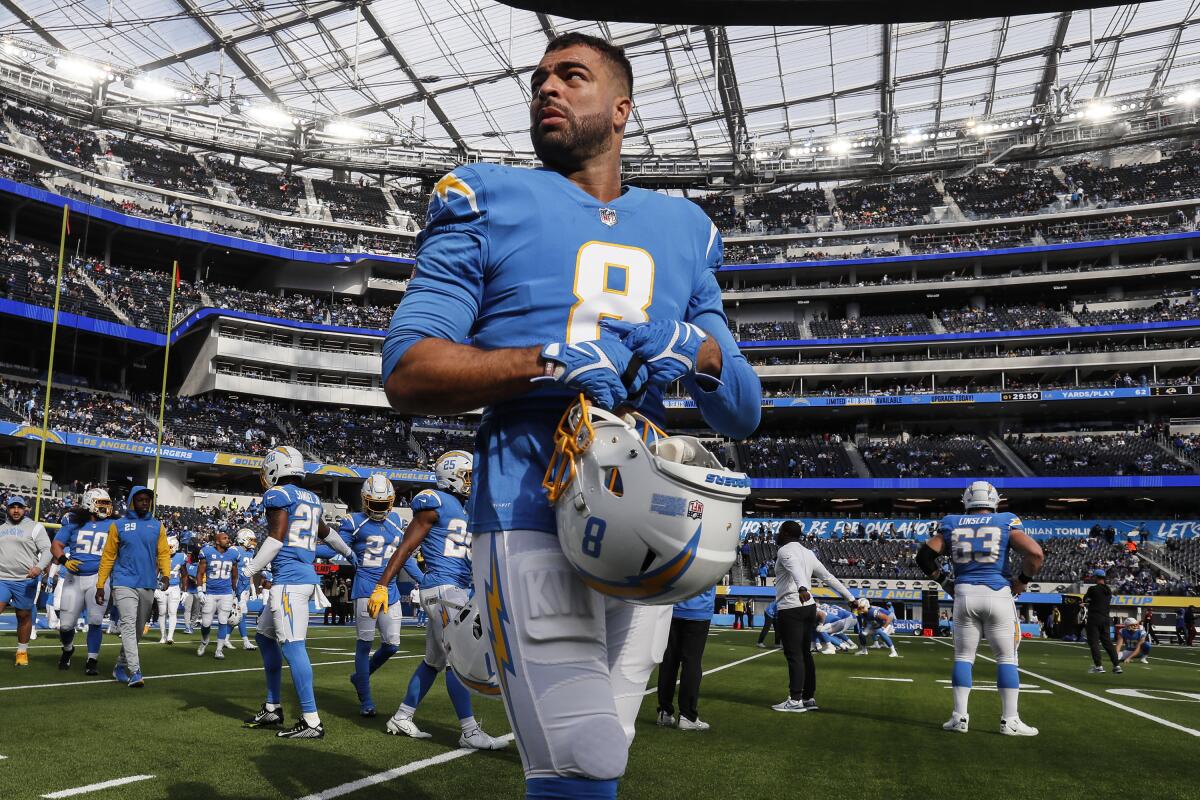 Chargers linebacker Kyle Van Noy walks on the field at SoFi Stadium as he holds his helmet.