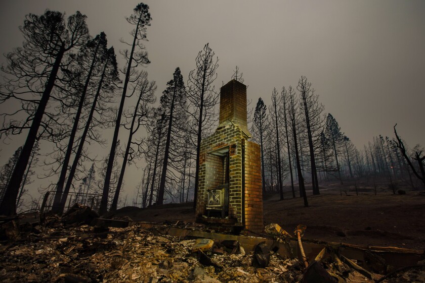 A burned out chimney stands in the rubble of a home