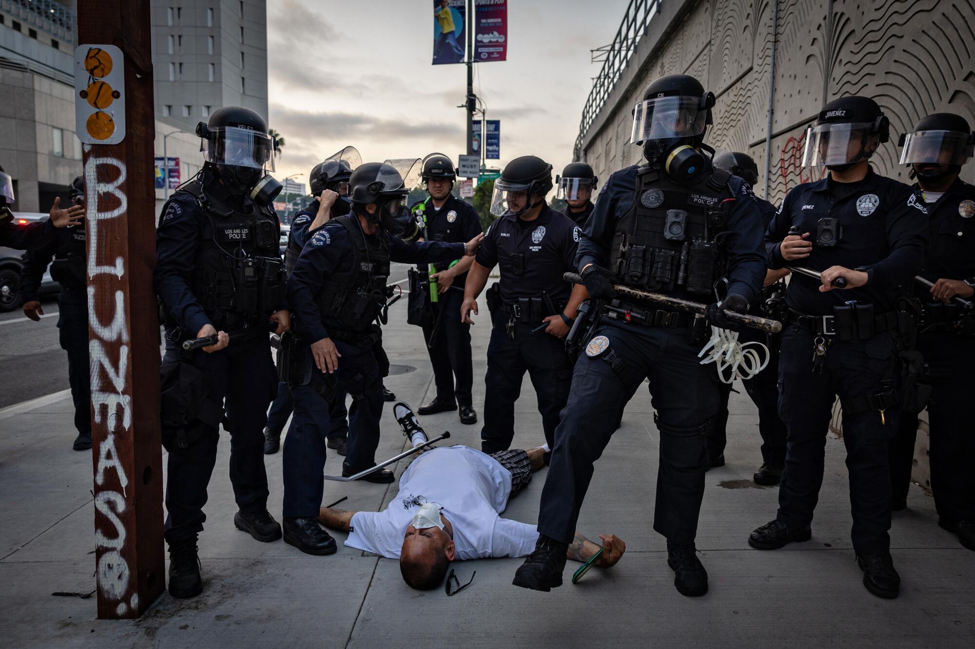 LAPD officers clear the streets and check on a man who fell down as protesters gather in response to ICE raids.