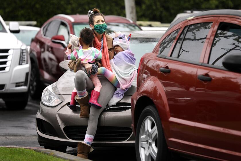 SANTA ANA-CA-APRIL 12, 2020: Ashley Amon, 33, and her daughters Alysha, 2, and Alexandria, 4, who are currently homeless, attend a gathering with fellow worshippers in their cars in a parking lot in Santa Ana to worship in an Easter service by Rev. Robert A. Schuller on Sunday, April 12, 2020. Schuller is reviving a practice that launched his father to worldwide acclaim- the drive-in ministry. For the past four years, the younger Schuller has been preaching primarily on social media, providing daily sermons from his "church with no walls." The COVID-19 outbreak - and the loss of in-person fellowship - led him back to his roots. "People need a place to go to worship on Easter, " he said. (Christina House / Los Angeles Times)