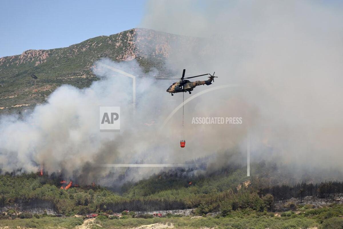 A helicopter sprays water to extinguish a fire in Seferihisar, near Izmir, Turkey