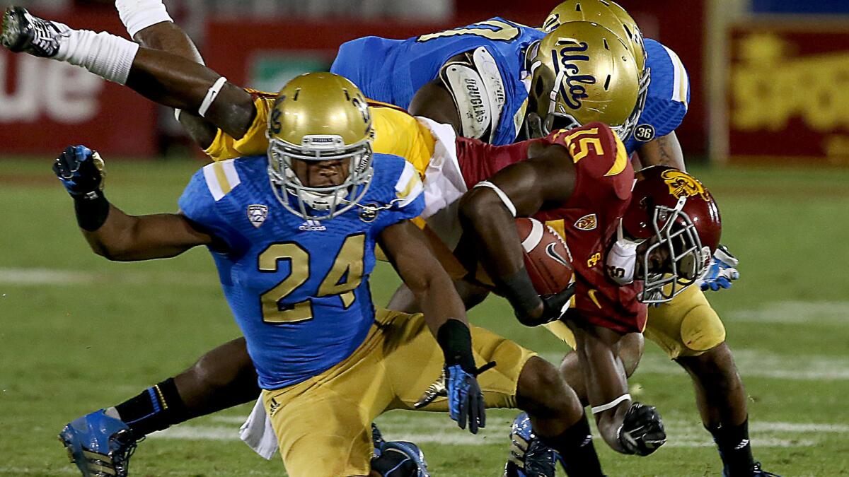 Ishmael Adams (24), Randall Goforth (background) and Myles Jack (30) bring down USC receiver Nelson Agholor during the 2013 rivalry game.