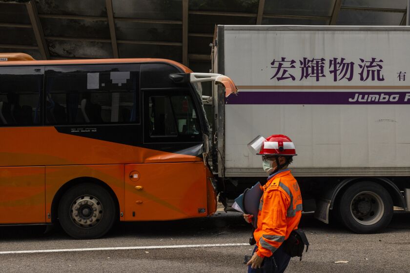 An ambulance worker inspects after an accident on a highway in Hong Kong, Friday, March 24, 2023. Four passenger buses and a truck collided near a Hong Kong road tunnel Friday, injuring dozens of people. (AP Photo/Louise Delmotte)