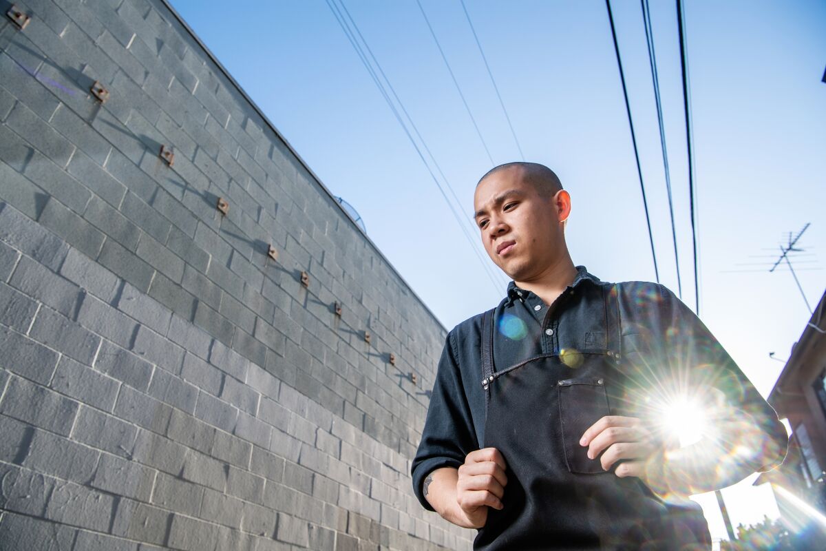 Kato chef-owner Jonathan Yao stands next to a concrete-block wall.