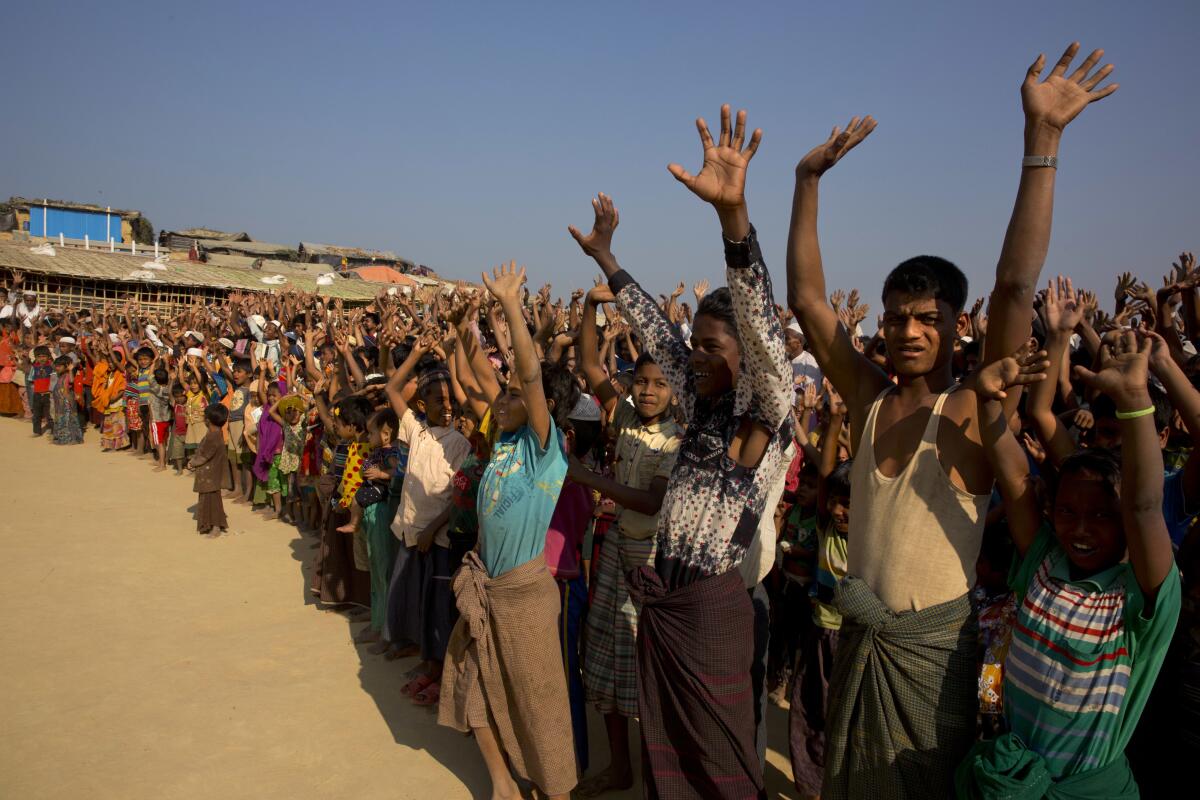 FILE - In this Jan. 22, 2018, file photo, Rohingya children and refugees raise their hands and shout that they won't go back to Myanmar during a demonstration at Kutupalong near Cox's Bazar, Bangladesh. Officials from the U.N. refugee agency and Bangladesh's government say few Muslim Rohingya refugees have responded to plans for their repatriation to Myanmar, and all who did say they don't want to go back. (AP Photo/Manish Swarup, File)