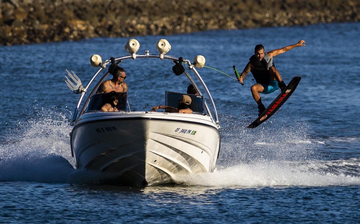 A wakeboarder gets air while being pulled behind a boat. 