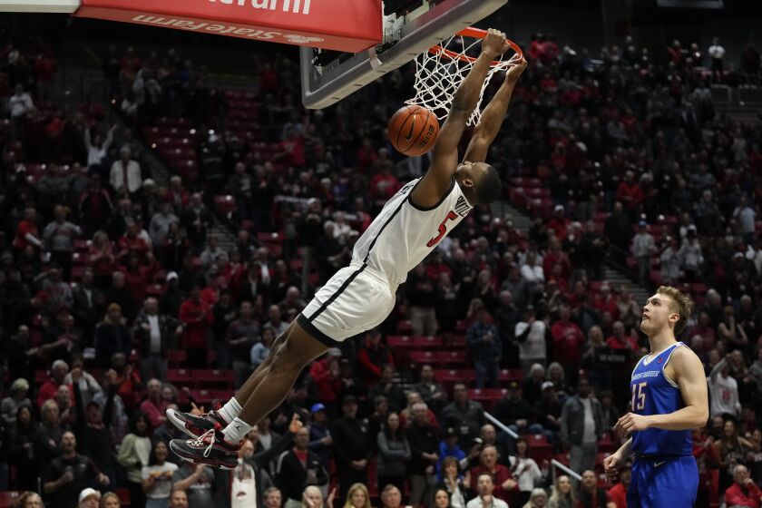San Diego State guard Lamont Butler dunks the ball as Boise State guard Jace Whiting looks on, right, during the first half of an NCAA college basketball game Friday, Feb. 3, 2023, in San Diego. (AP Photo/Gregory Bull)