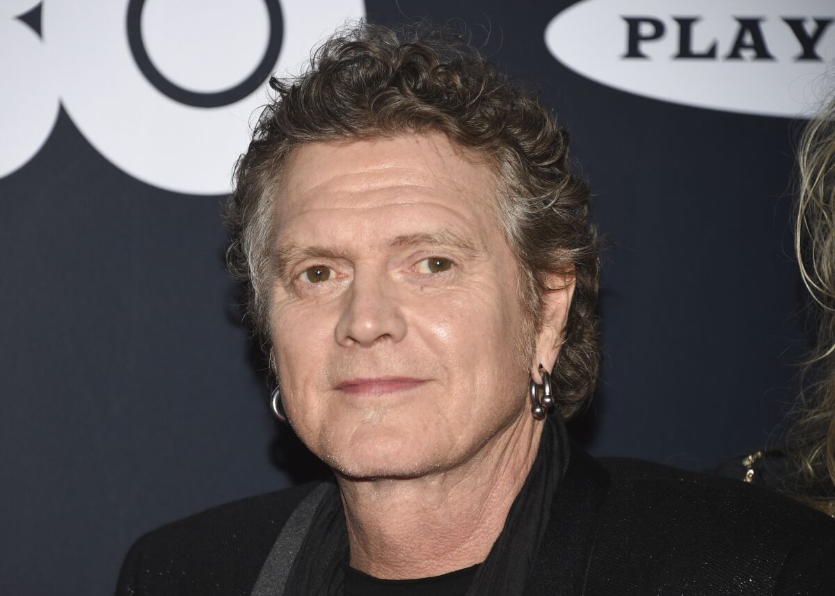 a man with graying hair and earrings.