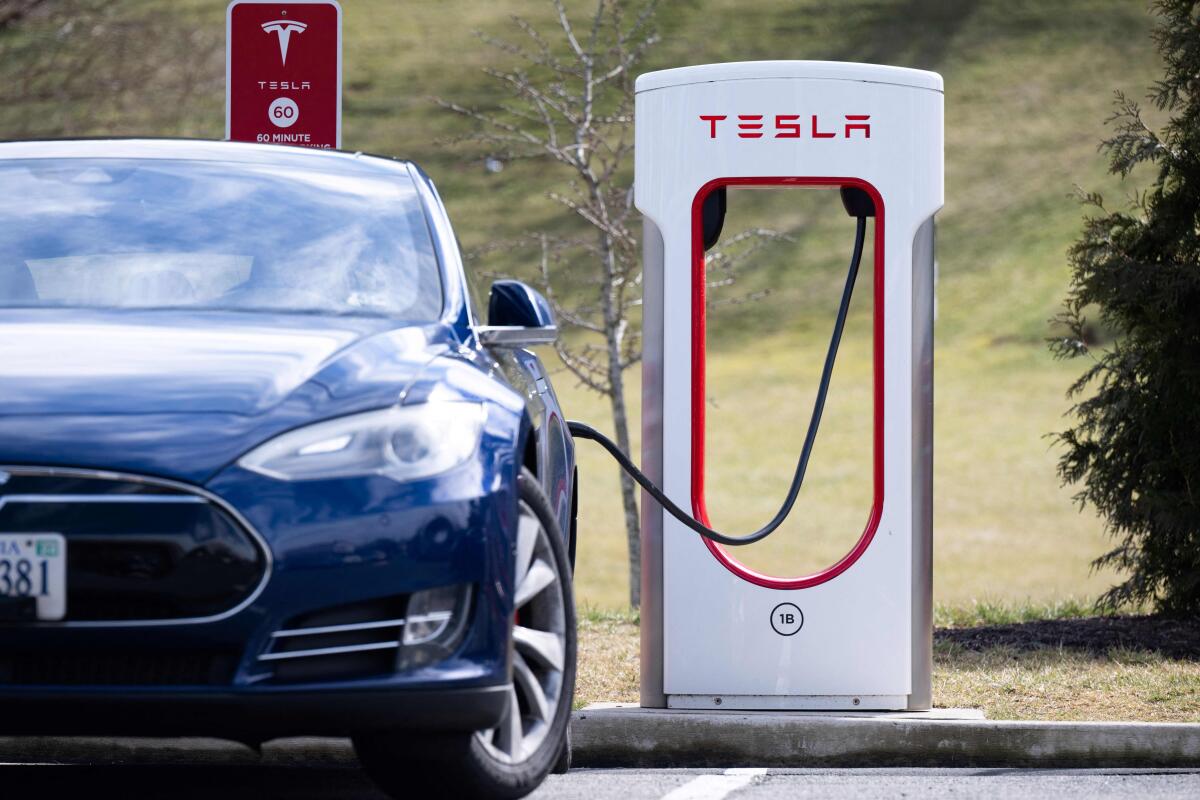 A car is plugged into a Tesla Supercharger. 