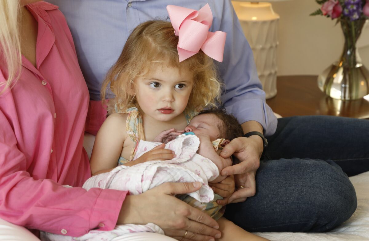 Two year-old Mary Boeckmann holds her new baby sister Vivian at home.