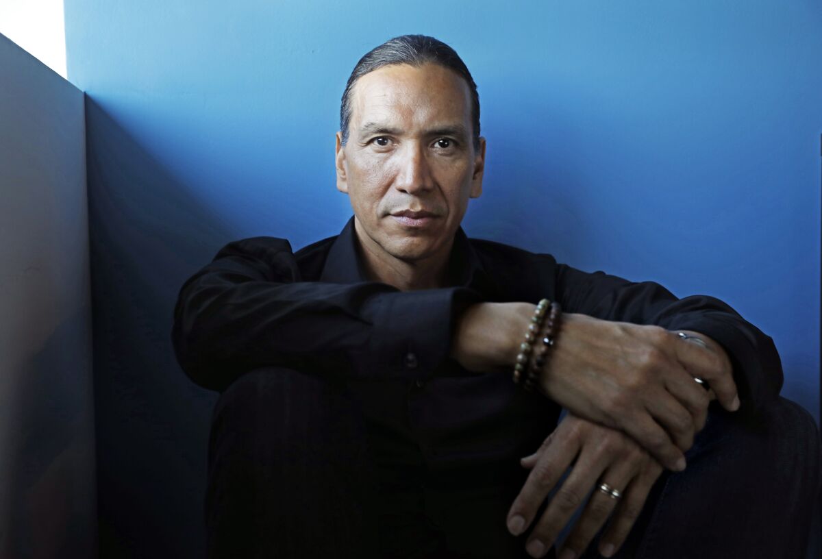 Actor Michael Greyeyes poses before a blue wall during a photo shoot in Los Angeles.