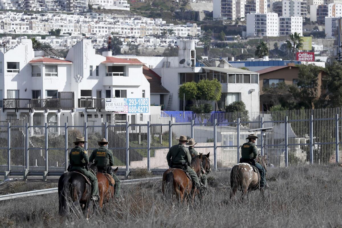 U.S. Border Patrol officers patrol on horseback near the border wall in Imperial Beach.