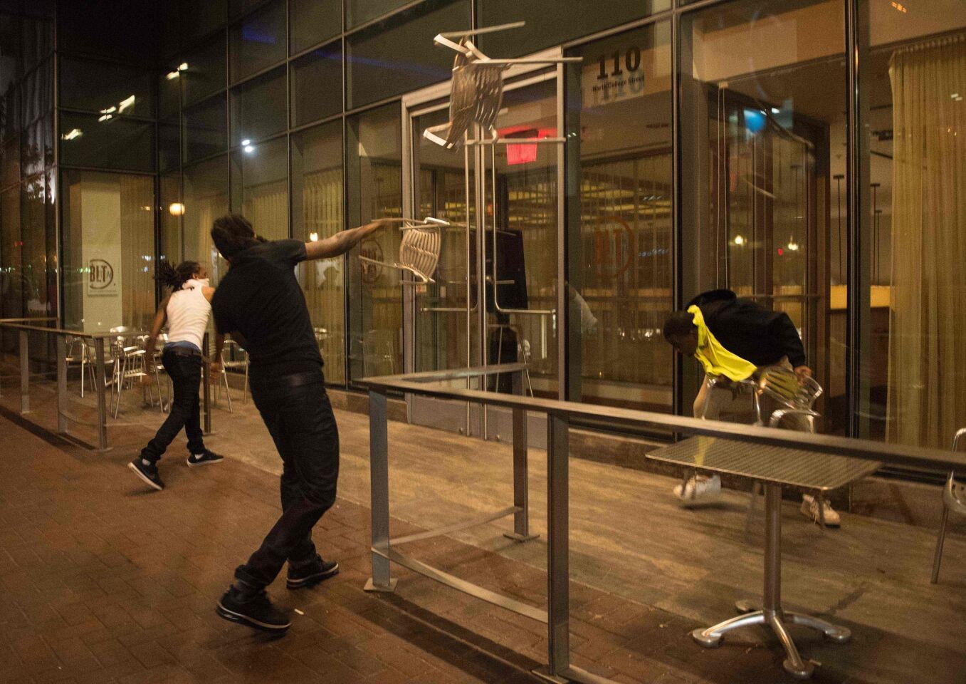 Protesters throw chairs at a restaurant during a demonstration against the use of deadly force by police in Charlotte, N.C.