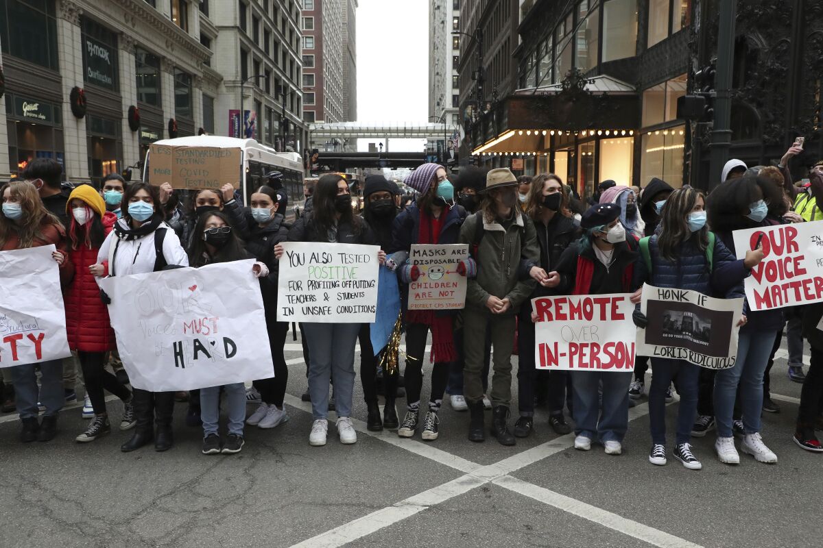 Protesters calling for better COVID-19 health and safety procedures in Chicago public schools briefly block traffic at State Street and Madison Street in Chicago near Chicago Public Schools headquarters on Friday, Jan. 14, 2022. (Terrence Antonio James/Chicago Tribune via AP)