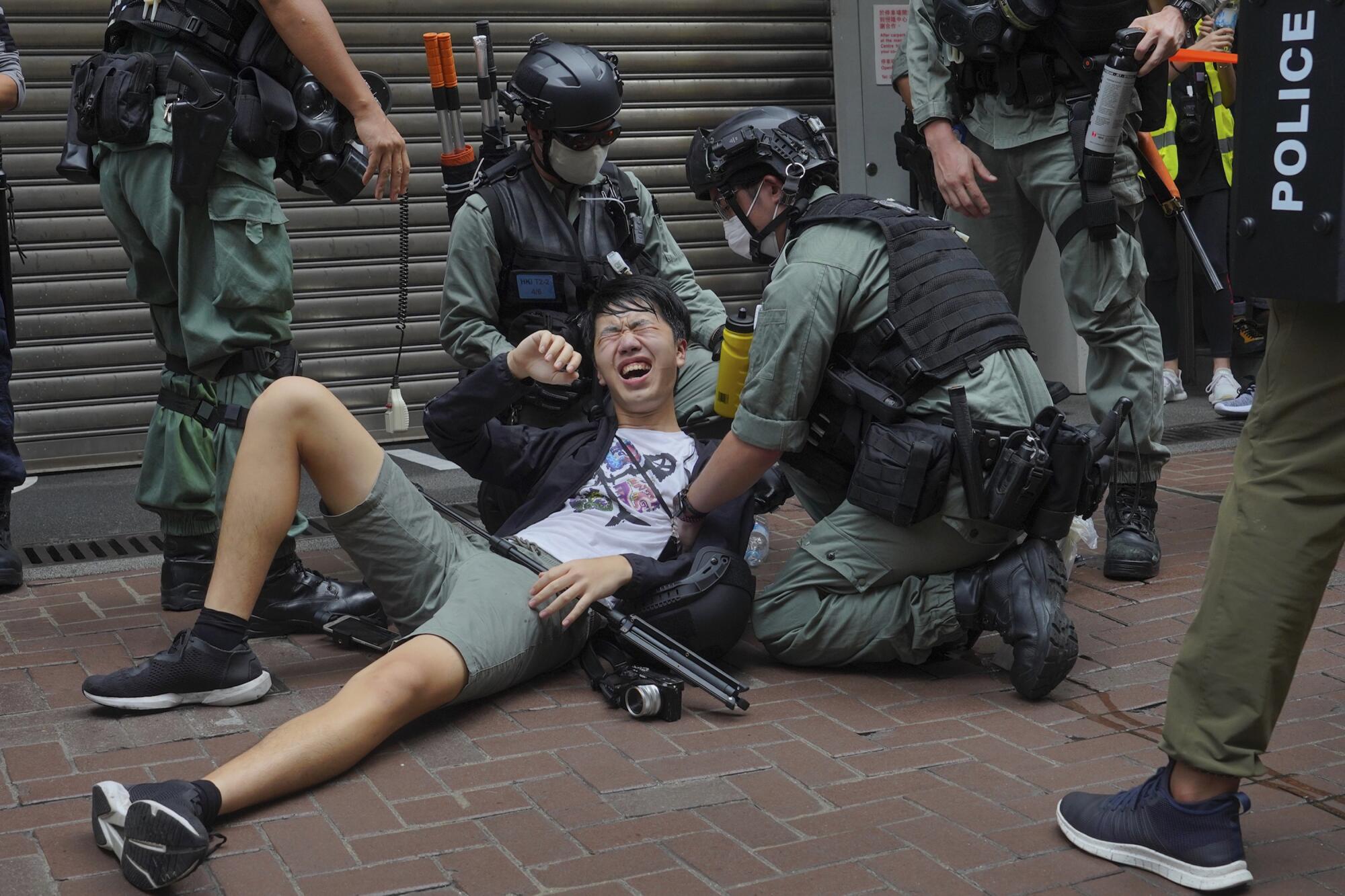 A reporter falls to the ground after being pepper sprayed by Hong Kong police during a protest in Causeway Bay on Wednesday.