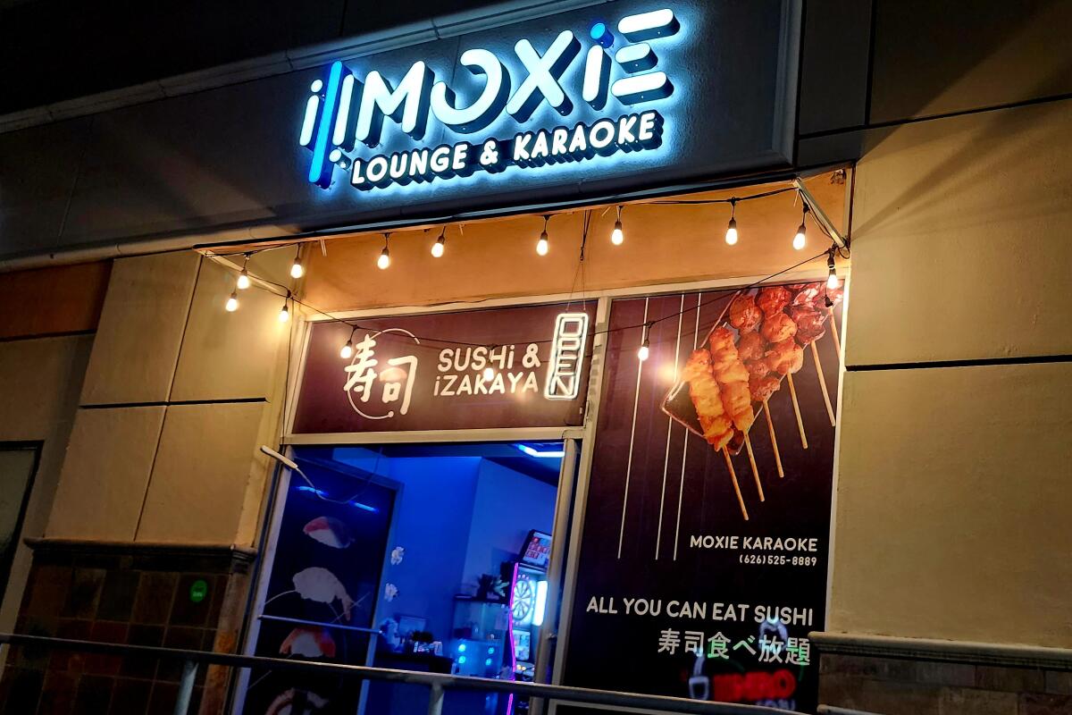 The outside of Moxie Lounge & Karaoke with a lighted sign.