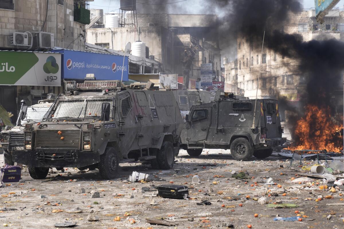 Smoke and Israeli armored vehicles in the West Bank city of Nablus