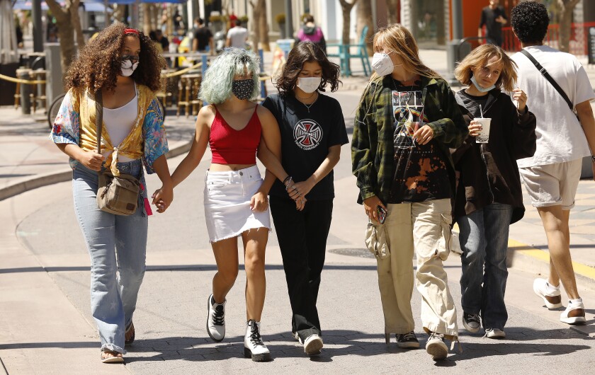 Young pedestrians with and without masks walk along the Third Street Promenade in Santa Monica 
