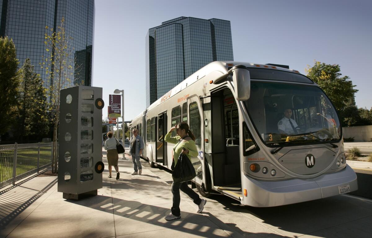 Morning commuters get off the Westbound Orange Line bus at the Warner Center Station in the West end of the San Fernando Valley. Enforcement has reduced the number of passengers riding the line for free.