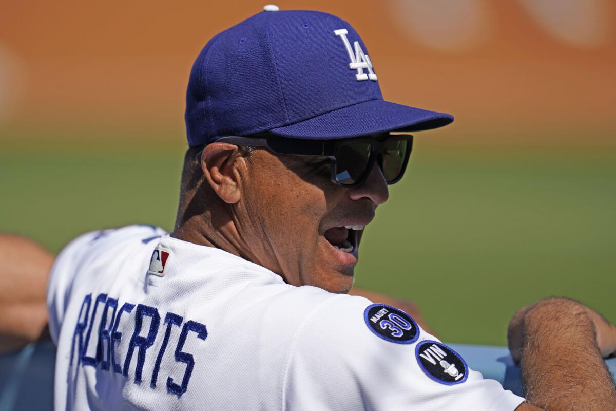 Dodgers manager Dave Roberts smiles in the dugout during Sunday's game against the Colorado Rockies.