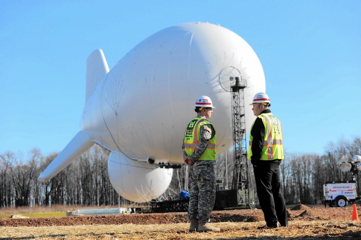 Officials stand before an aerostat at the Army's Aberdeen Proving Ground in Maryland. The aerostat, one of a pair to be floated in a three-year test, is part of a program to detect and aid in the shooting down of cruise missiles.