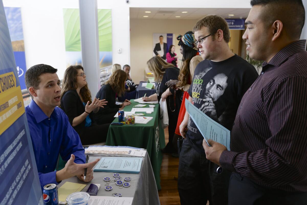 John Soung, right, and Gabriel Fitzgerald talk to recruiter Todd Zedicher of Integrated Life Choices at a job fair on the campus of Kaplan University in Lincoln, Neb., last month.