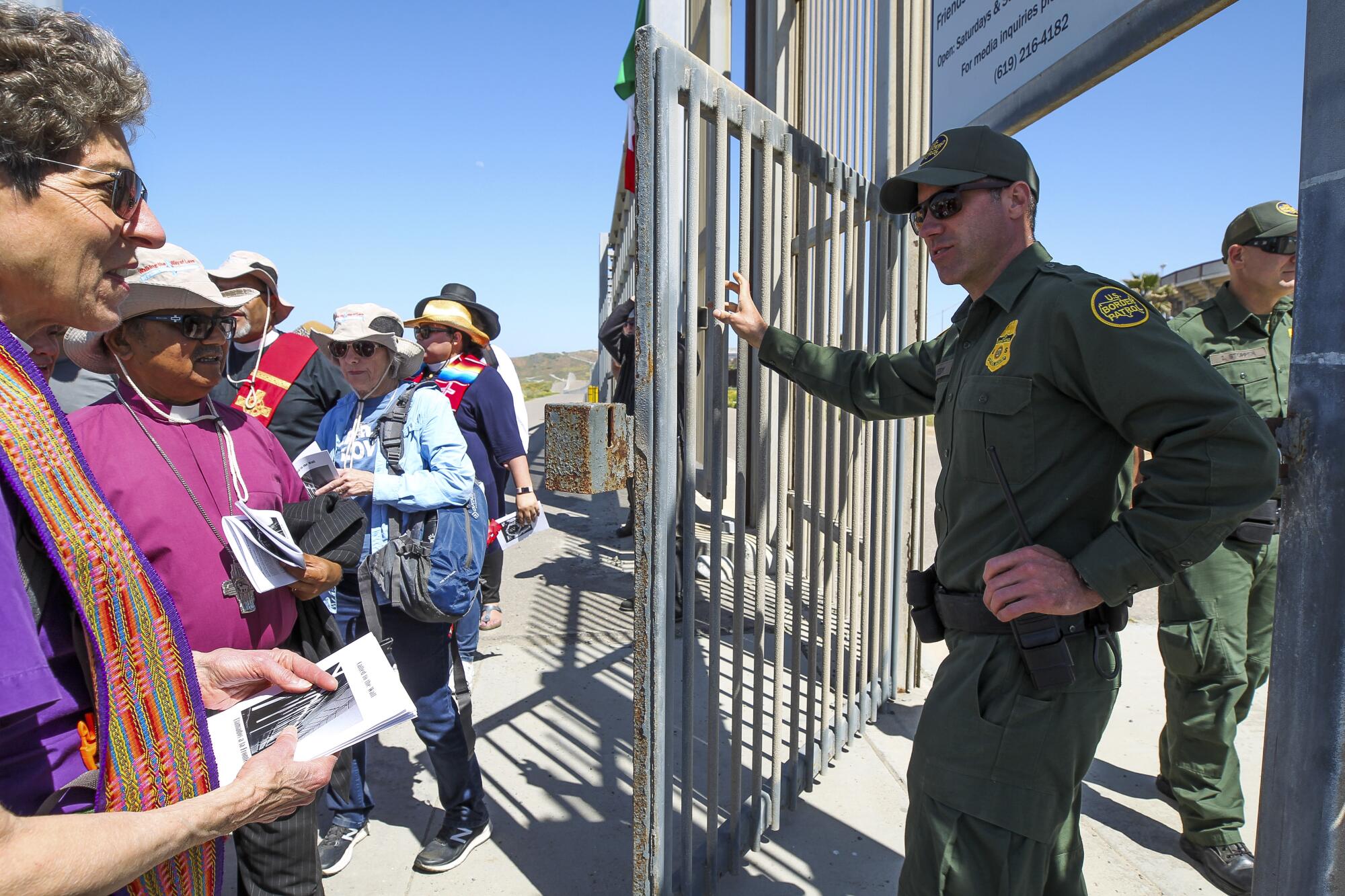 A Border Patrol agent opens a gate in the border fence.