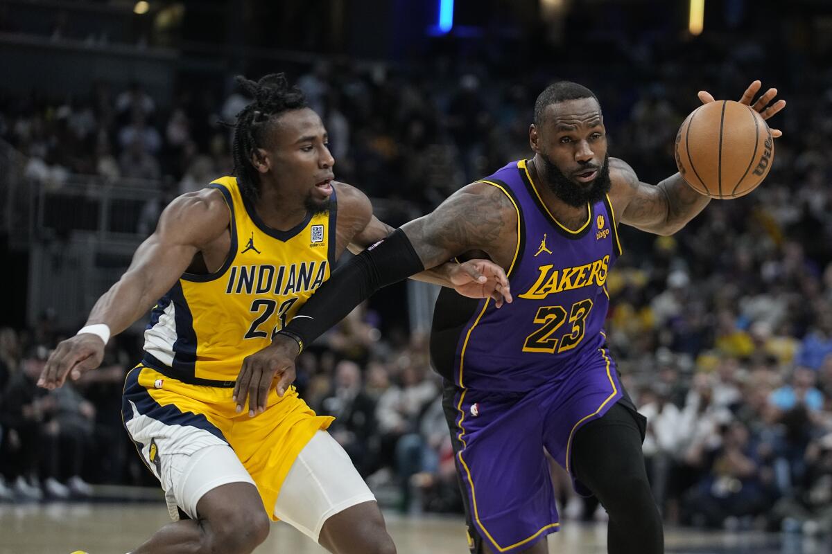 Lakers forward LeBron James, right, drives to the basket against Pacers forward Aaron Nesmith on Friday night.