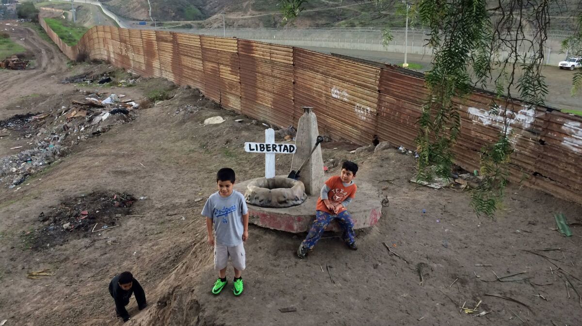 Kids play in view of the wall marking the U.S.-Mexico border — and a fiberglass sculpture bearing the name "Libertad."