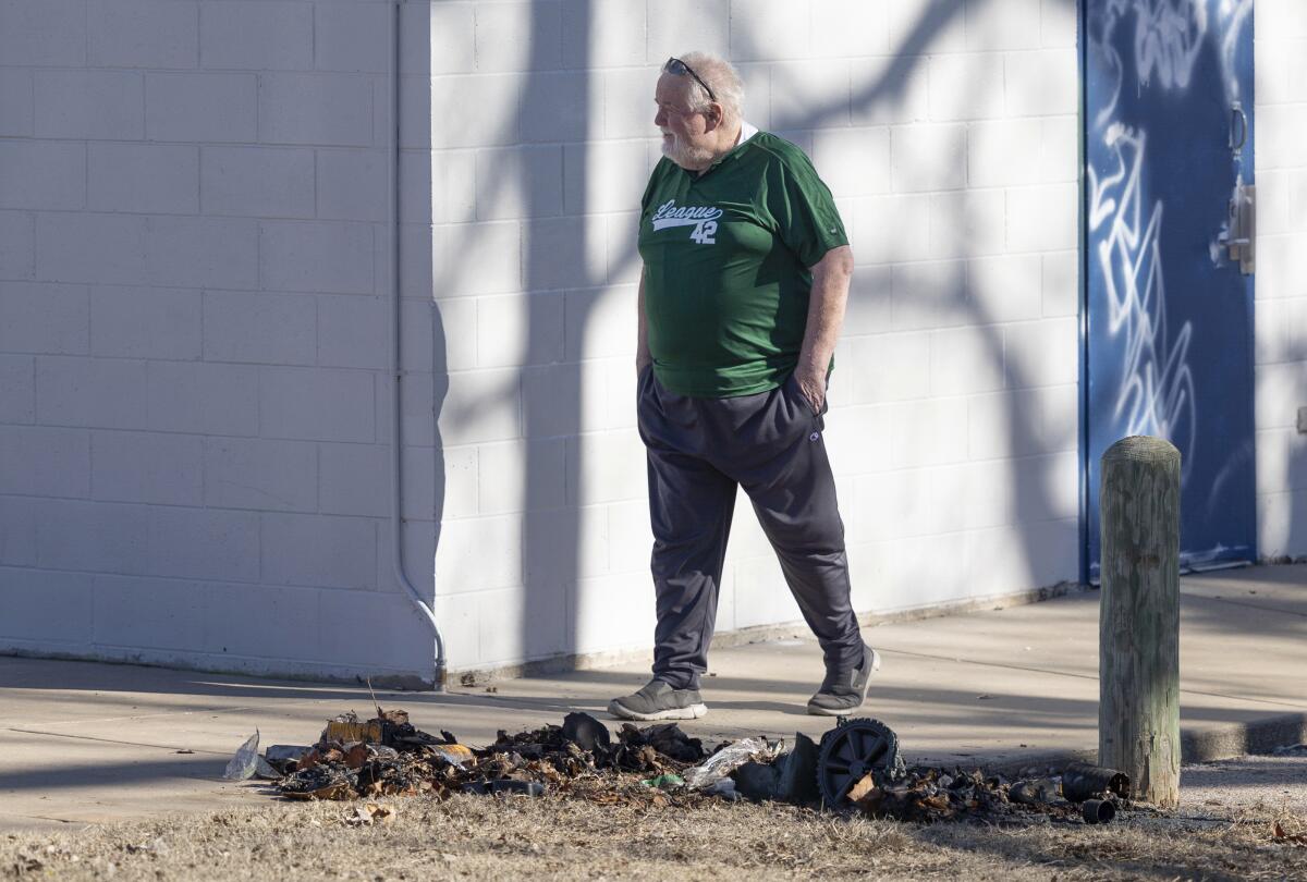 Bob Lutz walks past the charred remains of a trash can