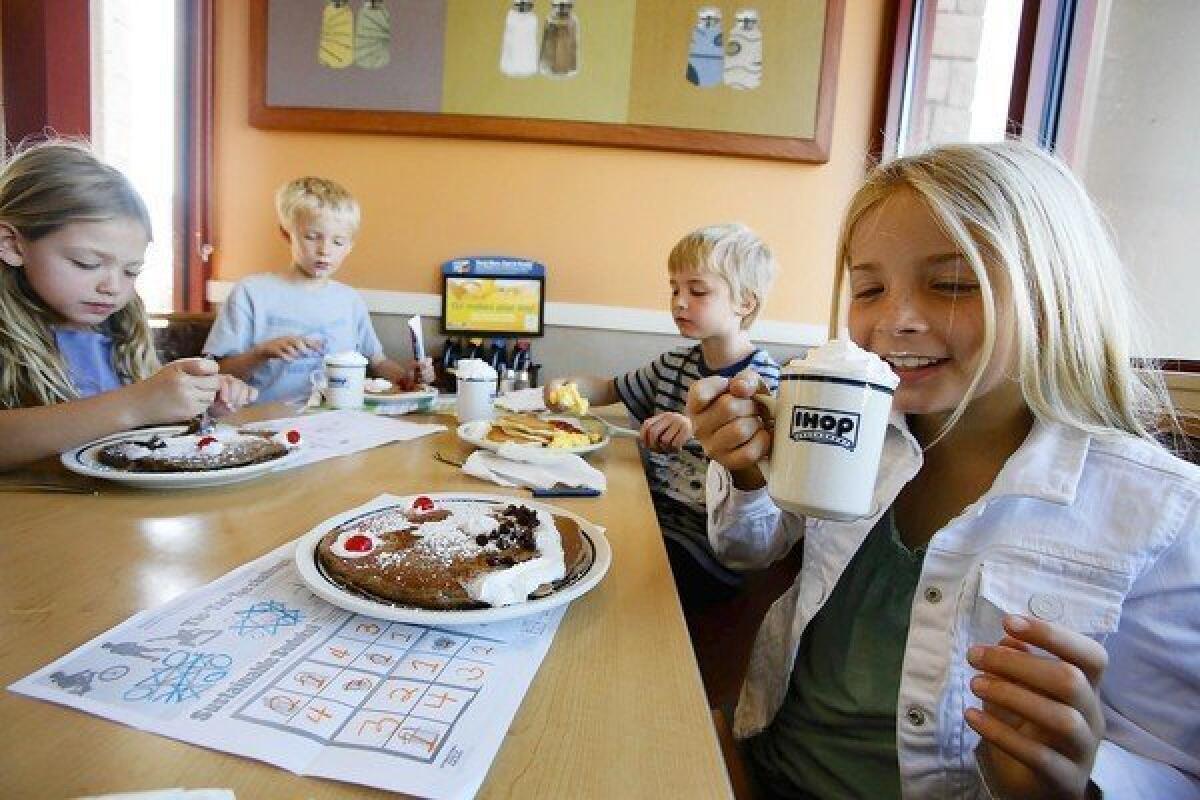 Marley Abowitz, 9, right, with her siblings 7-year-old Brody, Aidan and Ruby, 6, sips on a drink at IHOP restaurant in Los Angeles.