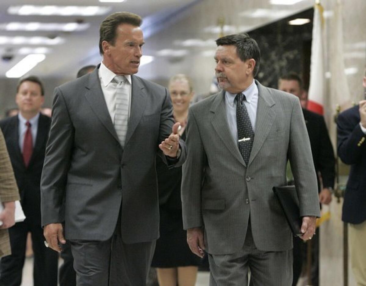 Gov. Arnold Schwarzenegger, left, talks with Finance Director Mike Genest as they walk to a news conference at which the governor released his revised state budget proposal.