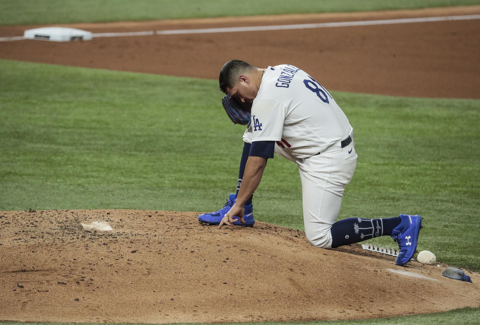 Dodgers reliever Victor Gonzálezwrites in the dirt on the pitching mound.